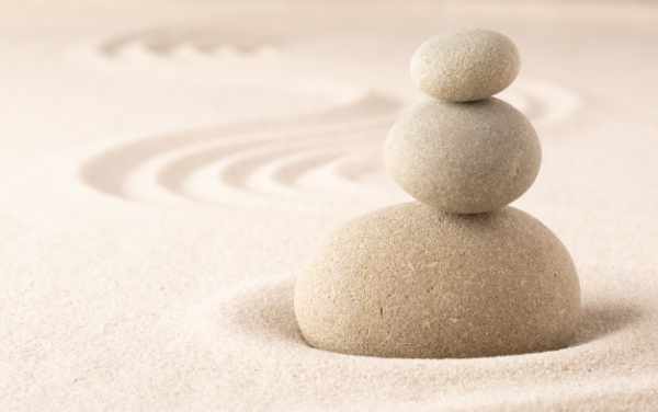 Three stacked Zen stones with sand